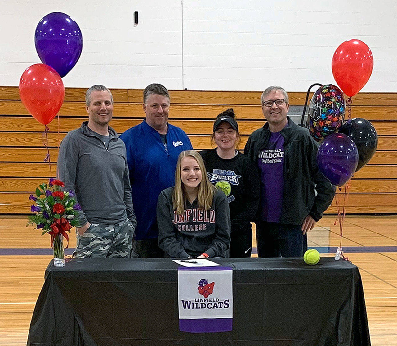 Elma softball player Molly Johnston, sitting, is flanked by her coaches after the senior signed a National Letter of Intent on March 17 to play for Linfield College in McMinnville, Ore. next season. Pictured are (from left): Travel ball coach Steve Poler, Elma head coach Roger Elliott, Elma assistant coach Ashley Stancil and travel ball coach Pat Pace. (Submitted photo)