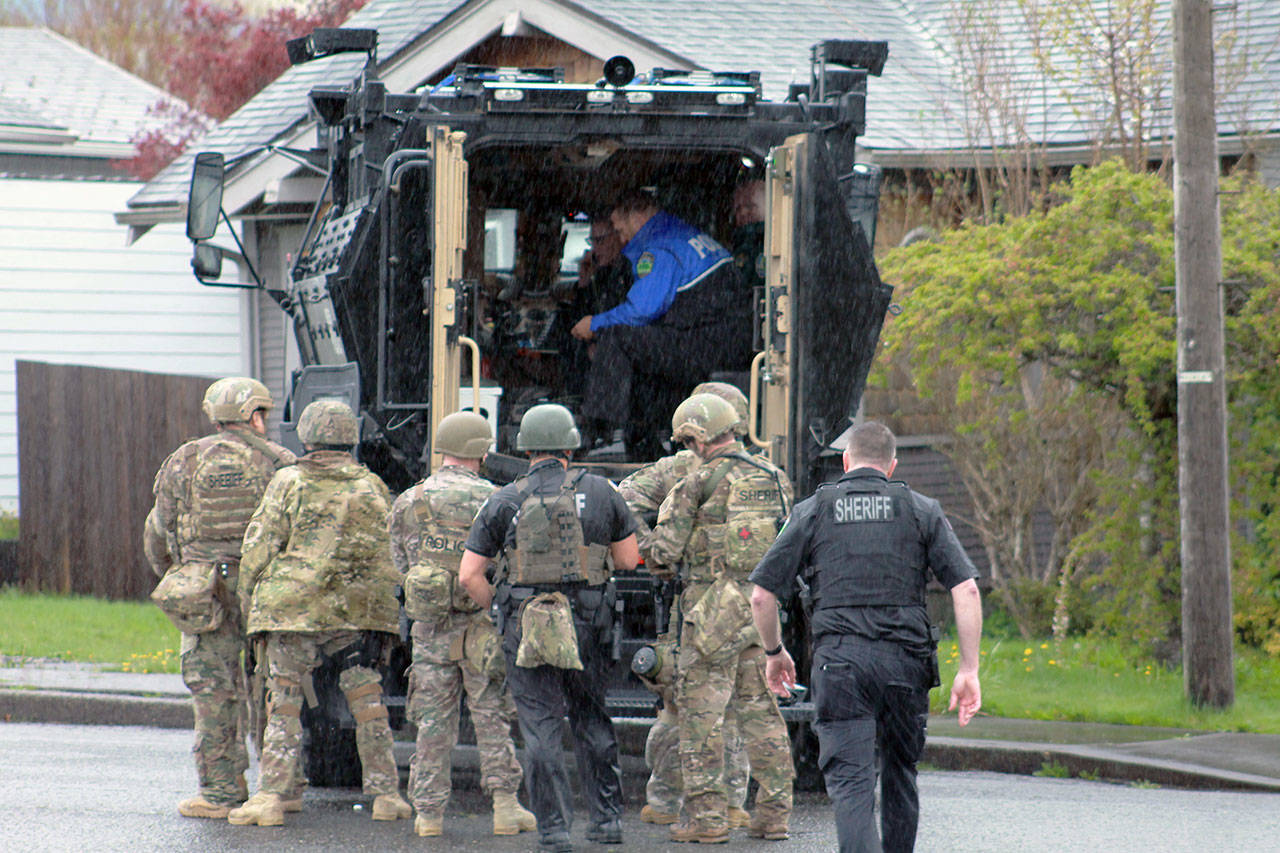 (Josh Jessen photo) Officers in camouflage armed with rifles took up positions on the west and south sides of the home as a negotiator attempted to bring the suspect out of the residence.
