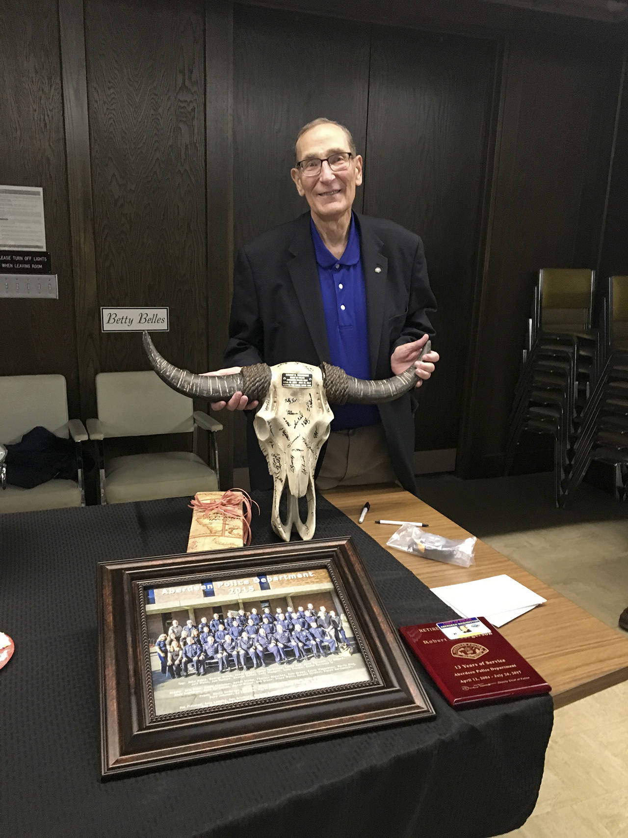 Ex-Aberdeen Police Chief Bob Torgerson poses with some of the gifts he received during a retirement reception, including a steer’s skull signed by everyone in his department.