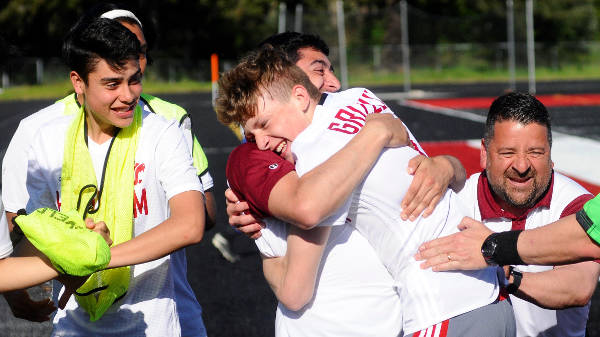 Hoquiam’s Cameron Bumstead hugs assistant coach Israel Fernandez on the sidelines after scoring a goal against La Center on Wednesday. (Hasani Grayson | Grays Harbor News Group)