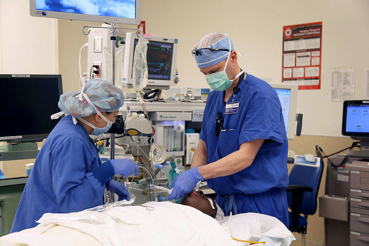 Dr. Brian Chesebro, right, in Portland, Ore., has calculated that by simply using the anesthesia gas sevoflurane in most surgeries, instead of the similar gas desflurane, he can significantly cut the amount of global warming each procedure contributes to the environment. (Kristian Foden-Vencil/OPB)