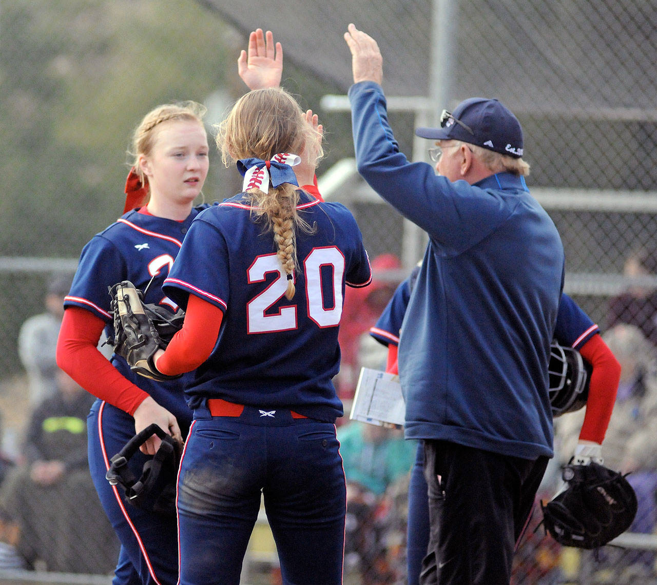 PWV pitcher Olivia Matlock, left, gets a high five from Britney Patrick (20) and head coach Ken Olson on March 23. The Titans begin 2B State Tournament play at 9 a.m. against Liberty Christian. (Ryan Sparks | Grays Harbor News Group)
