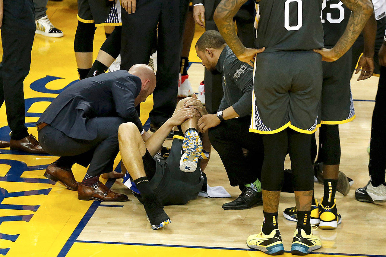 Klay Thompson of the Golden State Warriors is examined by trainers after hurting his leg against the Toronto Raptors in the second half during Game 6 of the NBA Finals on Thursday. (Lachlan Cunningham/Getty Images)