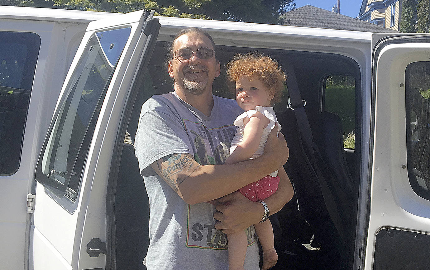 photos by DAN HAMMOCK | GRAYS HARBOR NEWS GROUP                                Family Promise van driver Micheal Schroeder holds young Family Promise resident Evelyn next to a van donated to the program by the Immanuel Baptist Church in Hoquiam.