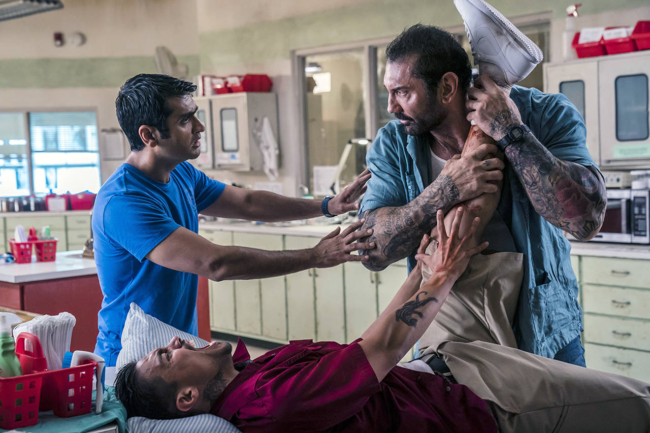 Kumail Nanjiani as Stu (left), Dave Bautista as Vic (right), and Rene Moran as Amo in a scene from “Stuber.”