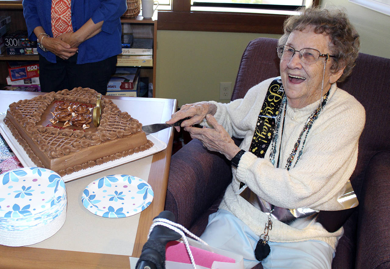 Photos by Dee Anne Shaw                                Ruth McCausland cuts the cake during her 100th birthday celebration in Olympia.