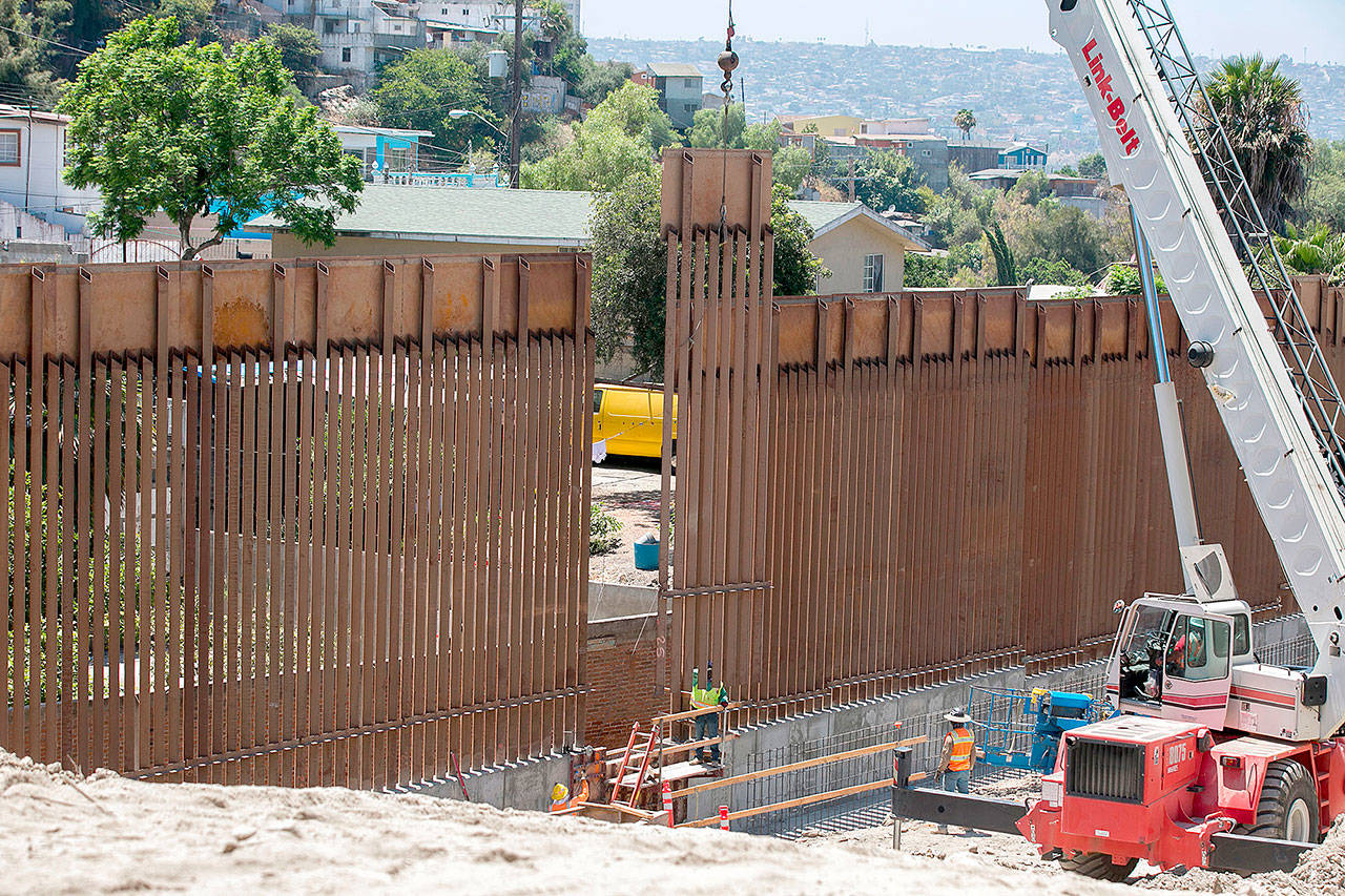 Crews move the last panel in the 14-mile, $147 million primary fence replacement project into place on Friday, just east of the San Ysidro Port of Entry in San Diego. (John Gibbins/San Diego Union-Tribune)