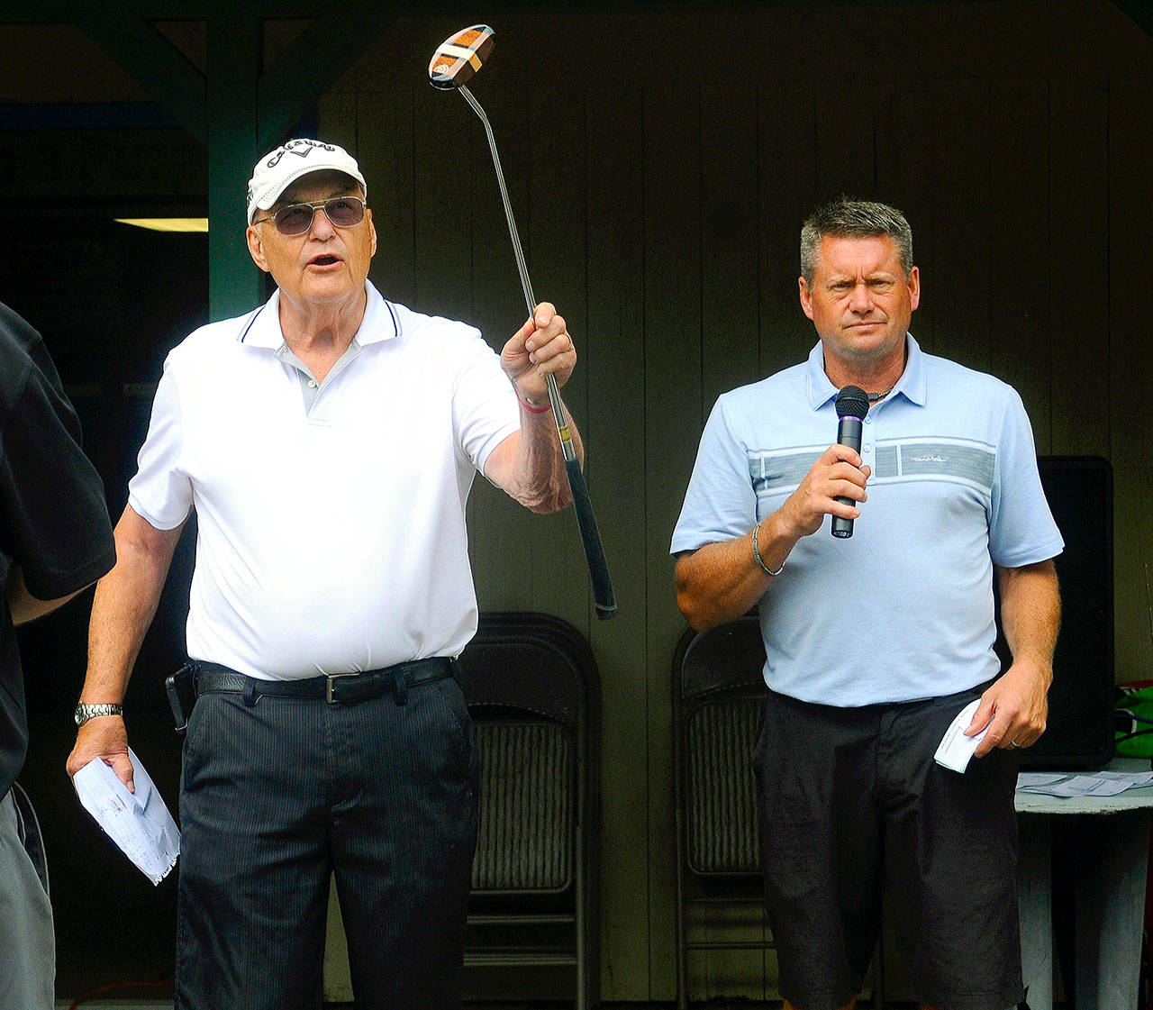 Take a Hack Against ALS Tournament chairman Harry Carthum, right, and Highland Golf Course Pro Ronnie Espedal auction off a putter at the conclusion of the charity golf tournament at Highland Golf Course on Saturday. (Hasani Grayson | Grays Harbor News Group)