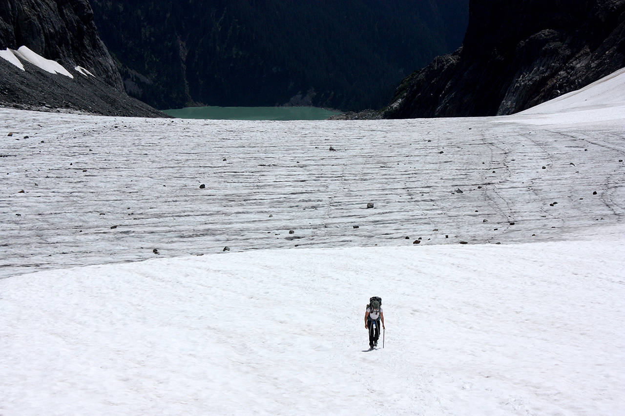 With Blanca Lake in the background, researcher Abby Hudak walks up to the northern end of Columbia Glacier. (Zachariah Bryan / The Herald)