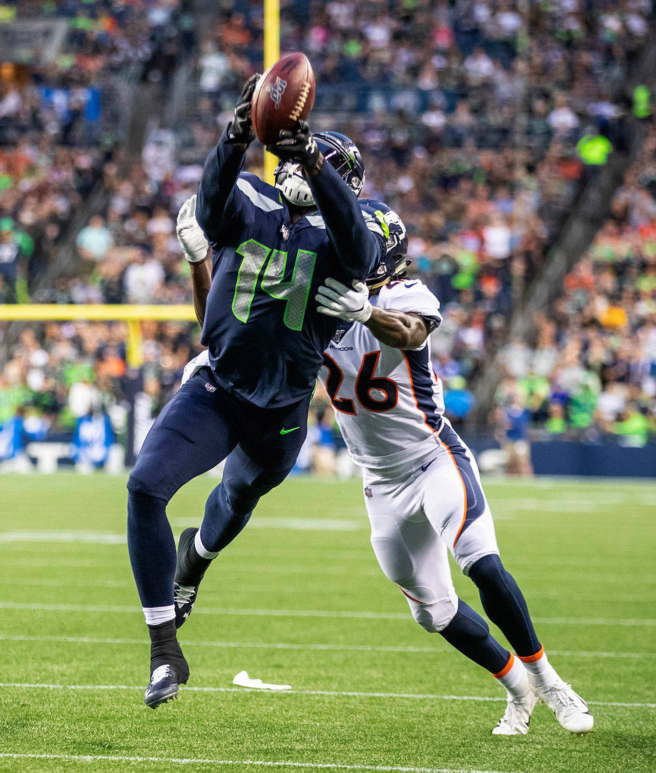 Seattle Seahawks wide receiver D.K. Metcalf (14) is unable to haul in a deep pass against the Denver Broncos Isaac Yiadoma (26) during a preseason game on Thursday, Aug. 8. The much-hyped second round pick had knee surgery on Tuesday. (Dean Rutz/Seattle Times/TNS)