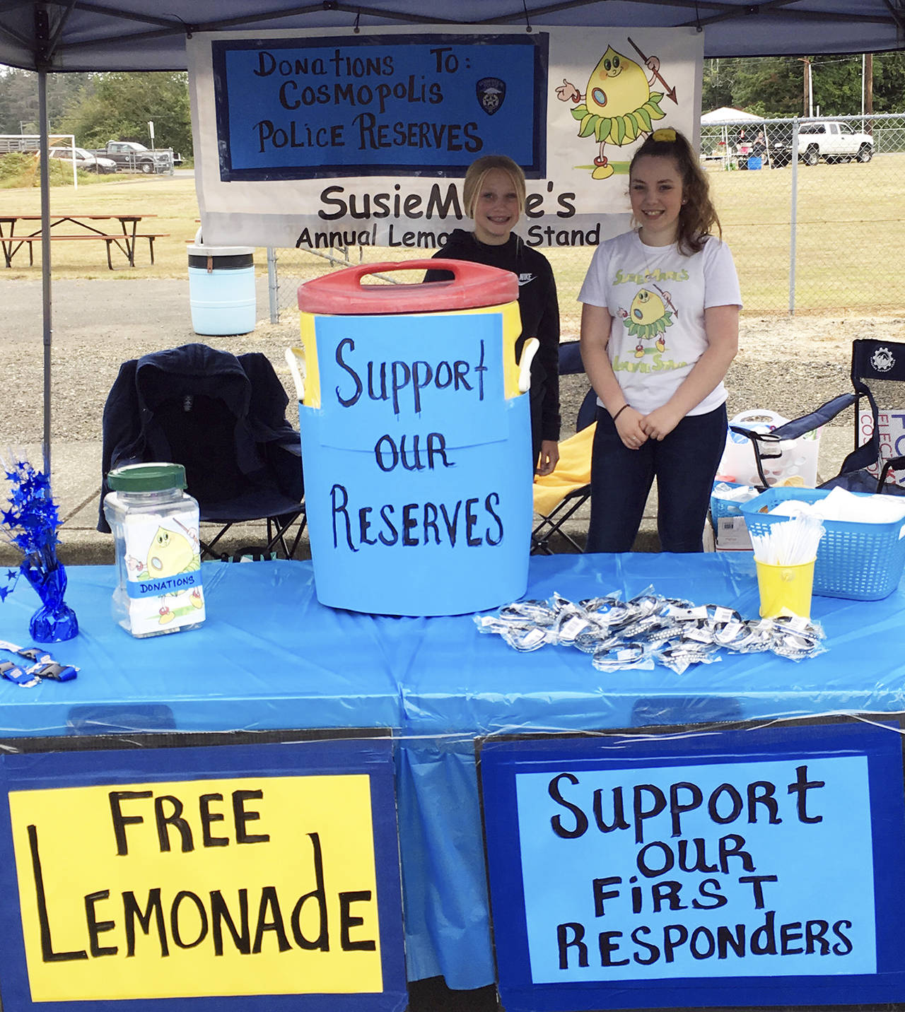 Courtesy photo                                SusieMarie’s Lemonade Stand, an annual fundraiser, pulled in nearly $2,200 Aug. 18 during the Festival in the Park in Cosmopolis. About $1,700 went to the Cosmopolis Police Department Reserves, and $500 went to the Cosmopolis Volunteer Fire Department. Pictured are SusieMarie Brenenstahl (at right) and Zoe Vessey, who helped run the stand this year. Next year, the 14th annual Lemonade Stand will be SusieMarie’s senior project — and it will be the last one, according to her grandmother, Ann Peery.
