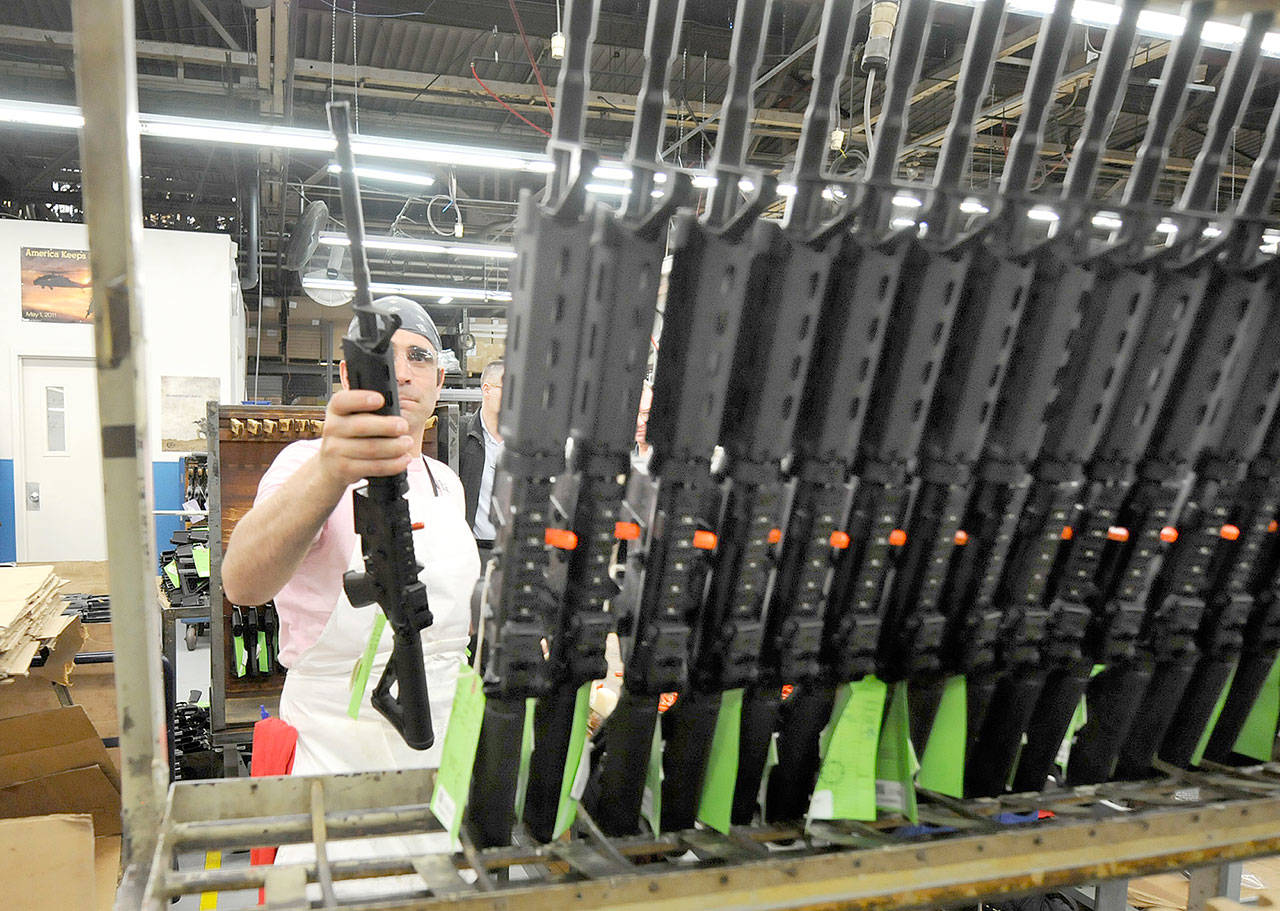 Sergio Pereira adds a completed Colt rifle to a rack of newly assembled guns at the company headquarters in West Hartford, Connecticut. The company said Thursday it was suspending production of AR-15 rifles for the civilian market. (Michael McAndrews/Hartford Courant)