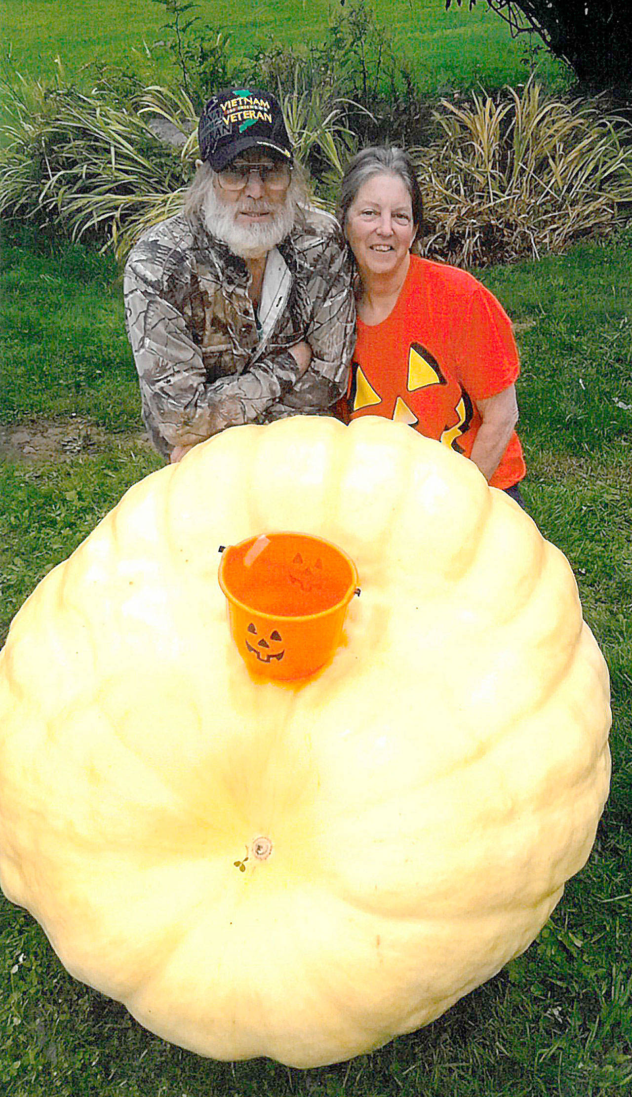 PHOTO COURTESY AMY FOWLER                                Vietnam veteran and retired millwright Larry Smith, here with his wife Michelle, shows off a 580-pound pumpkin he grew in his garden up the Wishkah. Smith’s stepdaughter, Amy Fowler, said Smith was challenged when his great-grandson was born 8 years ago to grow a pumpkin each year large enough for the child to fit in. The pumpkin is on display in front of Fowler’s home on Coolidge Road in South Aberdeen.