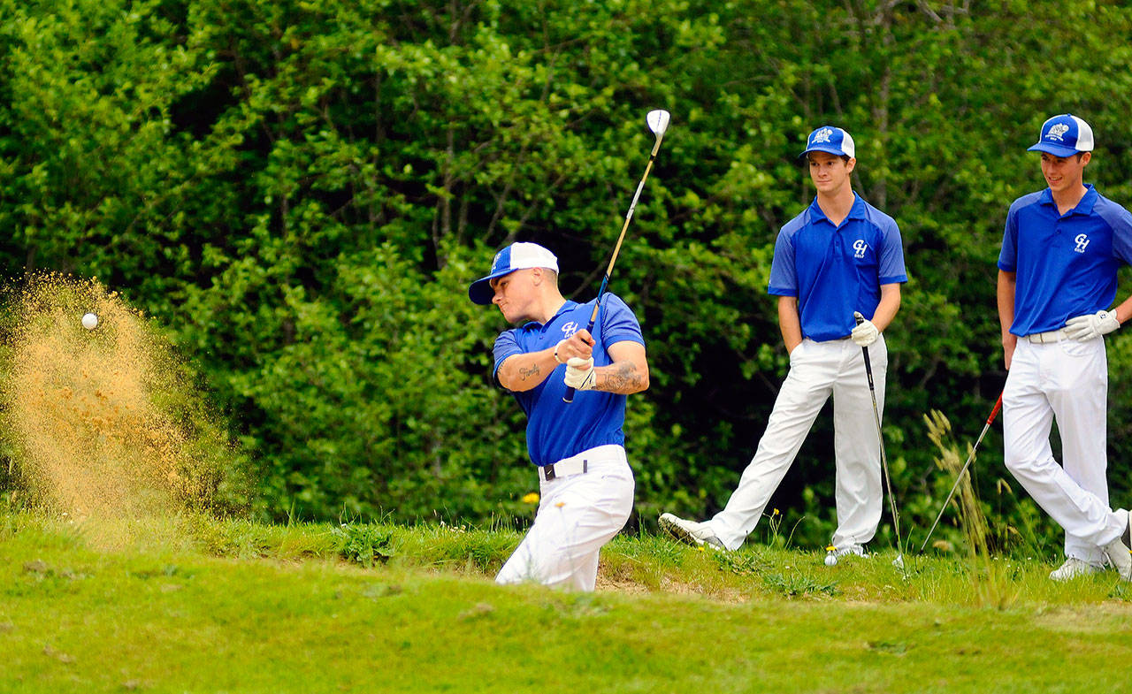 Grays Harbor’s Dylan Christoffer practices a bunker shot on the 18th hole at Highland Golf Course while Tim Nail and Cooper Benfield look on during a practice session on June 4. (Hasani Grayson | Grays Harbor News Group)