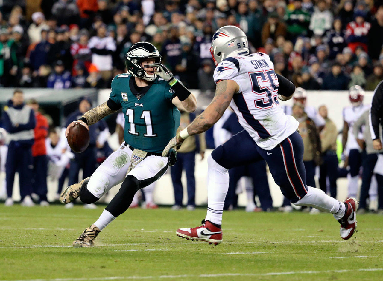 Philadelphia Eagles quarterback Carson Wentz (11) avoids New England Patriots defensive end John Simon on Sunday. (Tribune News Service)
