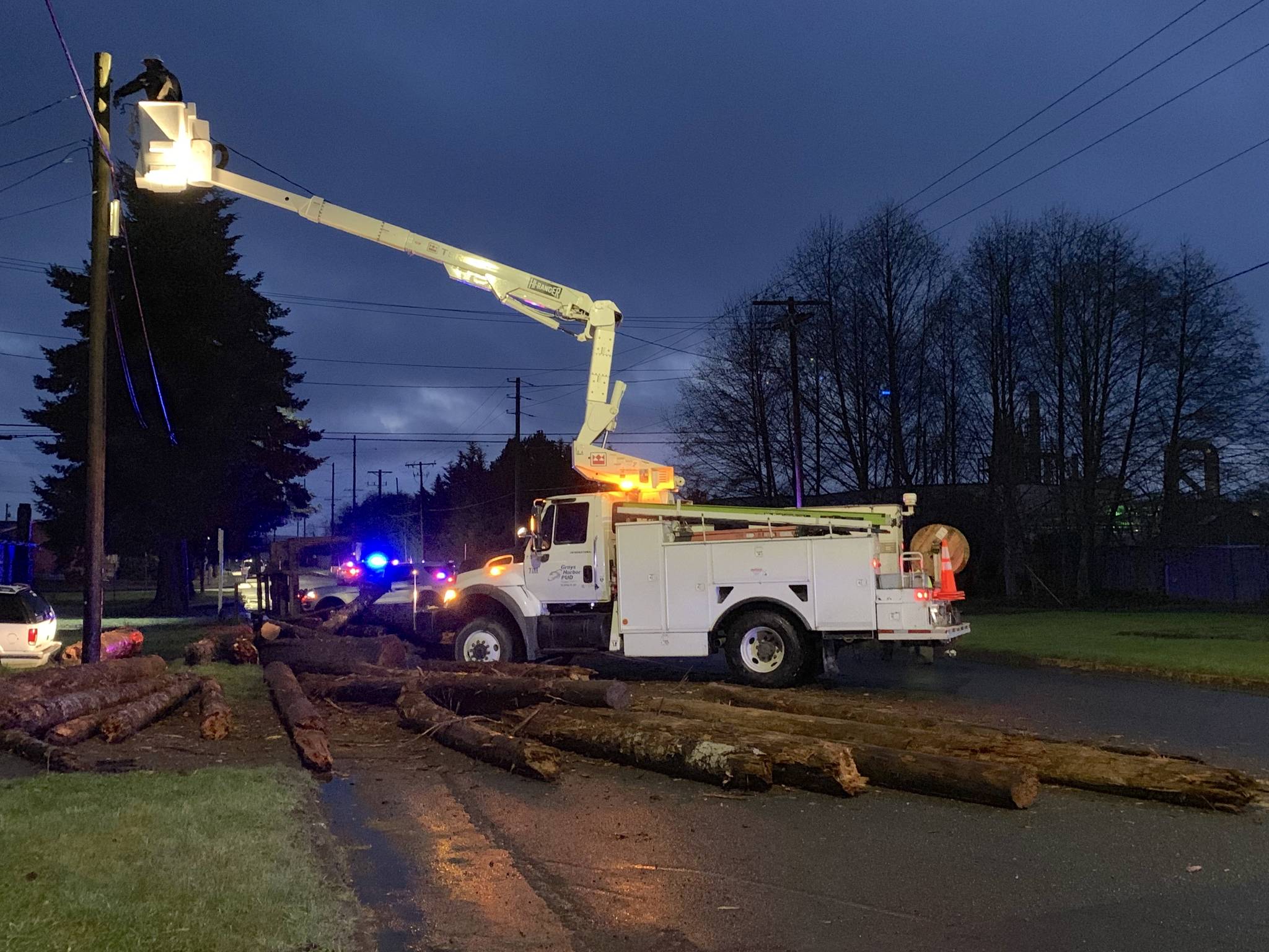 A PUD crew checks a power pole near the Simpson Avenue Bridge in Hoquiam Friday evening. A log truck lost its load going around a corner at 22nd Street and some of the logs rolled into the pole.