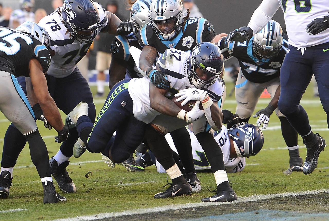 Seattle Seahawks running back Chris Carson (32) dives into the end zone for a touchdown as Carolina Panthers outside linebacker Shaq Thompson (54) tries to prevent it during the second half at Bank of America Stadium on Sunday. Seattle won 30-24. (David T. Foster III/Charlotte Observer/TNS)