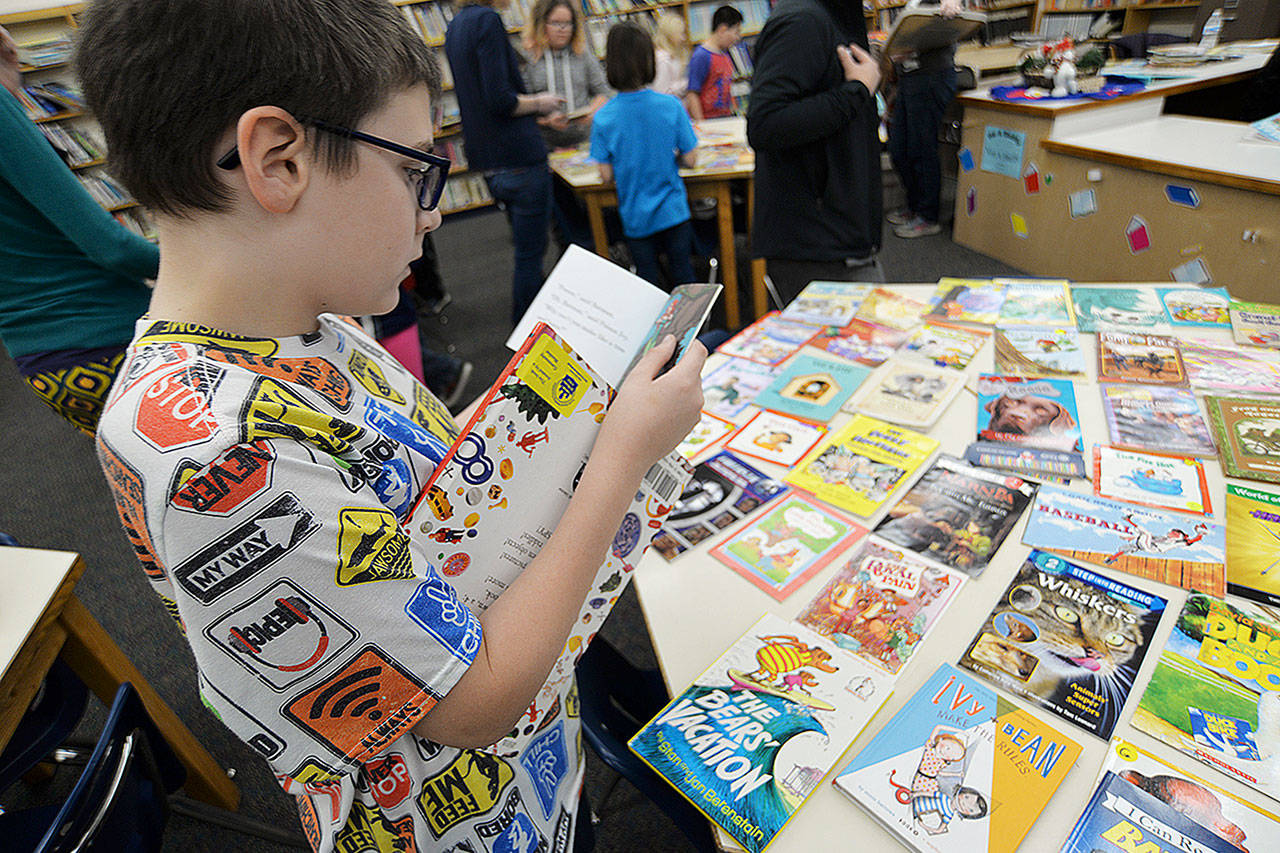 Photos by Thorin Sprandel | Grays Harbor News Group                                Fourth-grader Chance Howell browses at books during a giveaway at the Cosmopolis Elementary School library Monday morning.