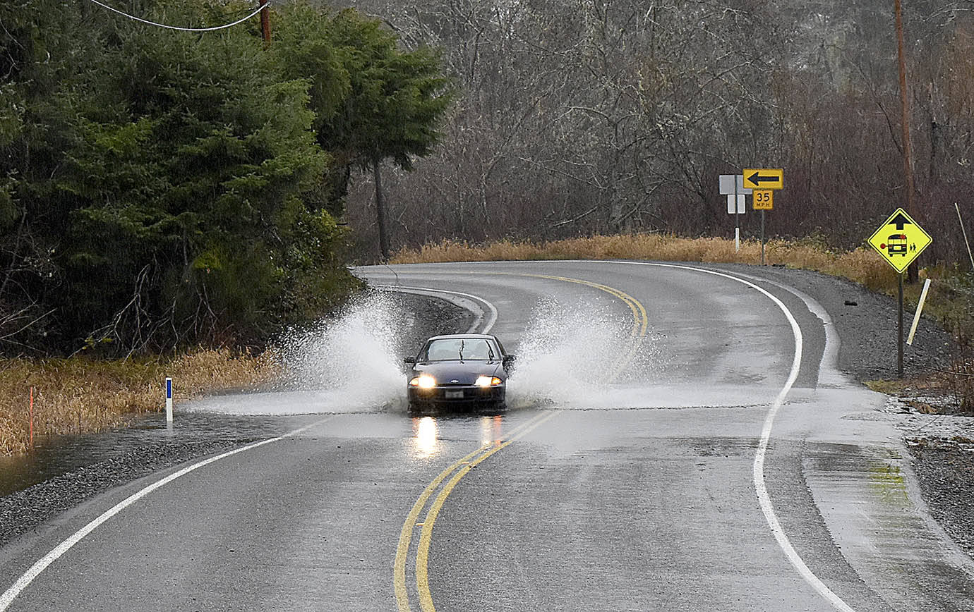 DAN HAMMOCK | GRAYS HARBOR NEWS GROUP                                A car plows through water crossing the roadway a few miles up the Wishkah north of Aberdeen Thursday. Heavy rains and high tides caused some localized flooding in the region, and a flood watch remains in effect in Grays Harbor County through 10 p.m. Sunday.