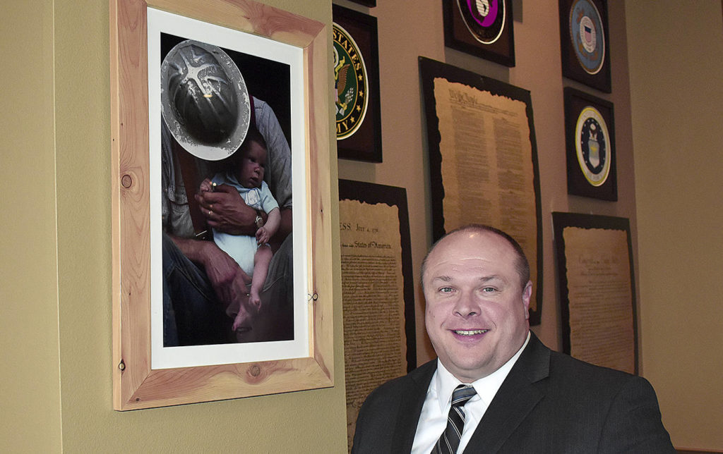 DAN HAMMOCK | GRAYS HARBOR NEWS GROUP                                Hoquiam Mayor Ben Winkelman stands by a photo of his dad, Mario Winkelman, and his youngest brother Bryce taken at Camp Grisdale the year it closed, which hangs in the Jitter House in Hoquiam. The Winkelman family had its roots in the logging camp.