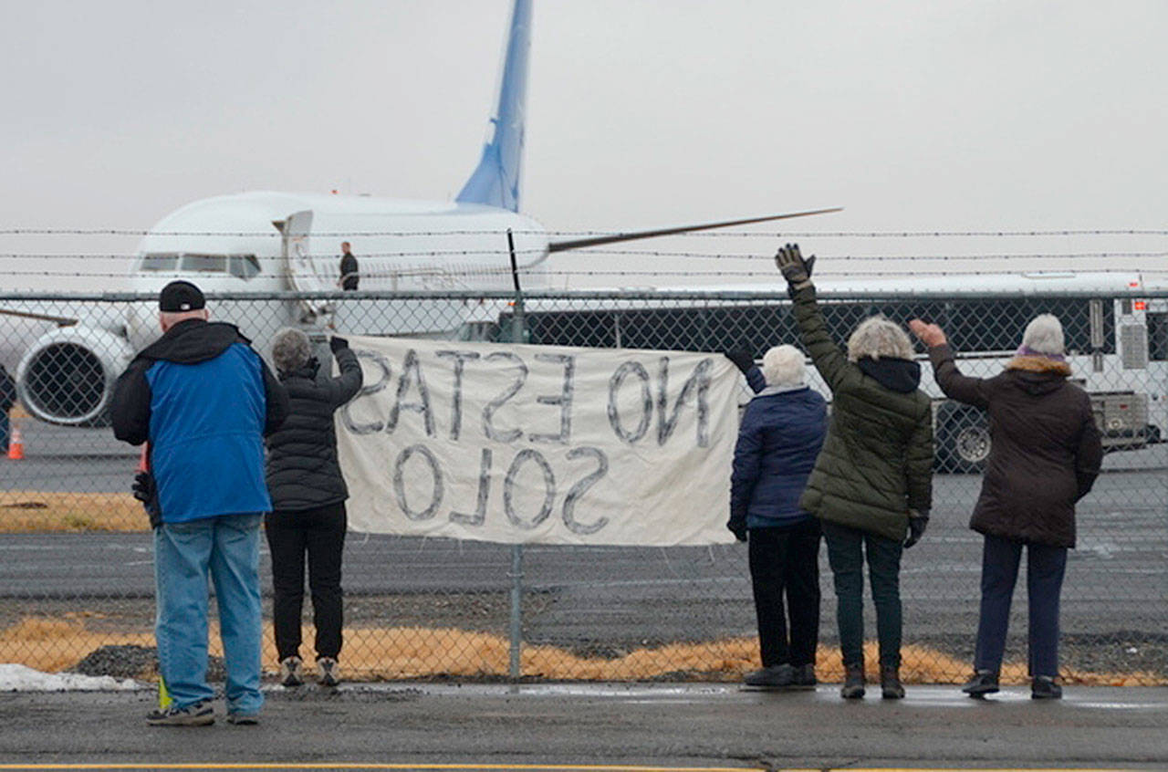 Activists in Yakima, wave encouragement Dec. 10 to a detainee in shackles boarding a U.S. Immigration and Customs Enforcement flight bound for El Paso. (Richard Read/Los Angeles Times)