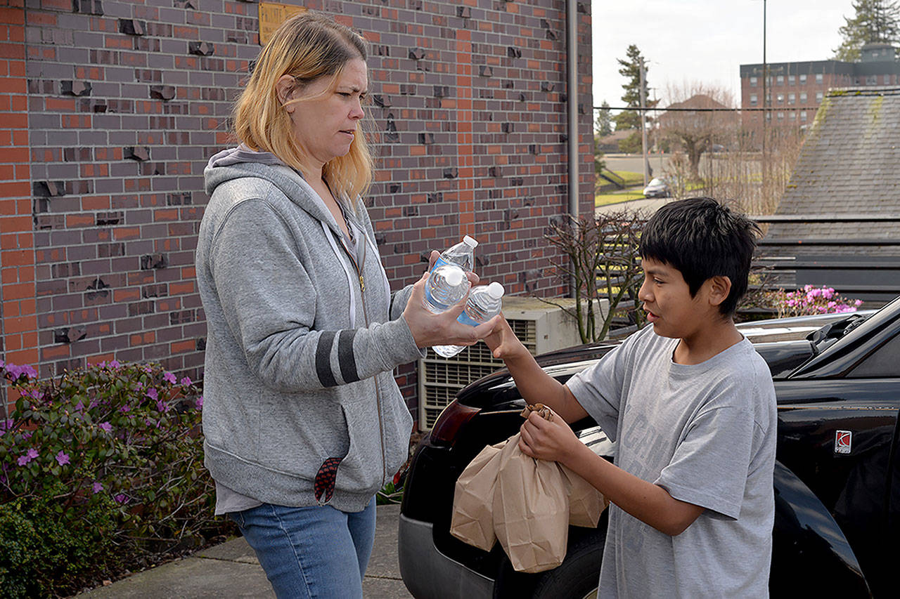 Feed the Hungry program director Cher Keller passes out lunches to Benito Rodriguez behind the St. Mary’s Catholic Church on Wednesday. (Thorin Sprandel | Grays Harbor News Group)