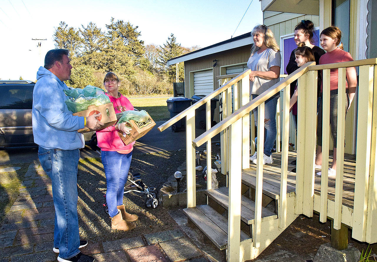 Kevin and Diana Schneeloch, founders of the Ocean Shores Cares nonprofit, bring bags of fresh food to Debbie Heinke and her family. Her health issues have made her among many in Ocean Shores who are self-quarantining to avoid exposure to the COVID-19 virus. (Photo by Scott D. Johnston)