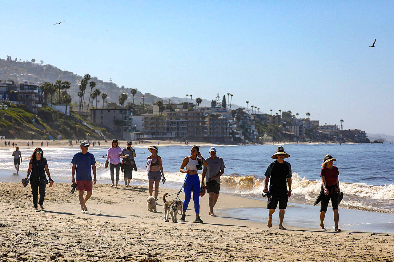 People stroll along Laguna Beach on Tuesday morning as the city, with the state’s blessings, reopened its beaches for active use only. The first phase of the reopening includes 6-10 a.m. hours Mondays through Fridays. (Irfan Khan/Los Angeles Times)