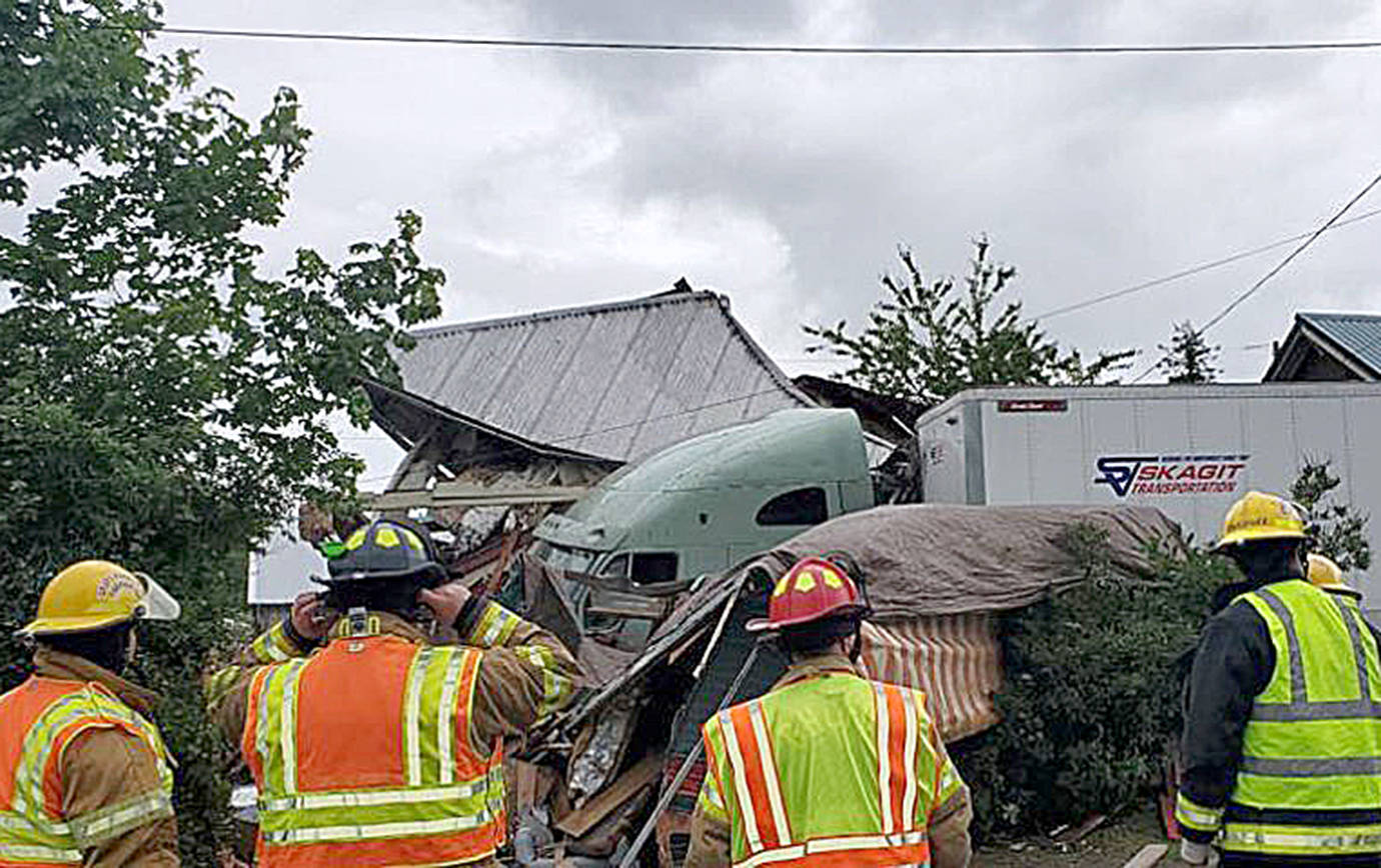 COURTESY GRAYS HARBOR FIRE DISTRICT 5                                 Emergency personnel assess the damage after a two-semi wreck on State Route 12 in Malone Friday afternoon sent one rig through a fence and into two homes and a residential travel trailer.