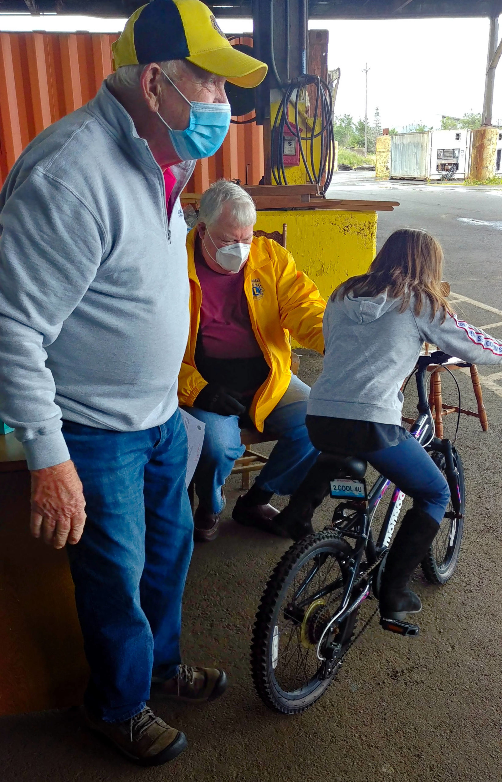 Photo by Kelly Peterson                                Stafford Creek Corrections Center Aberdeen Lions Club members (from left) Gene Schermer and Bob Braden watch as a recipient of the Bicycles from Heaven program test rides their new bike on June 12.