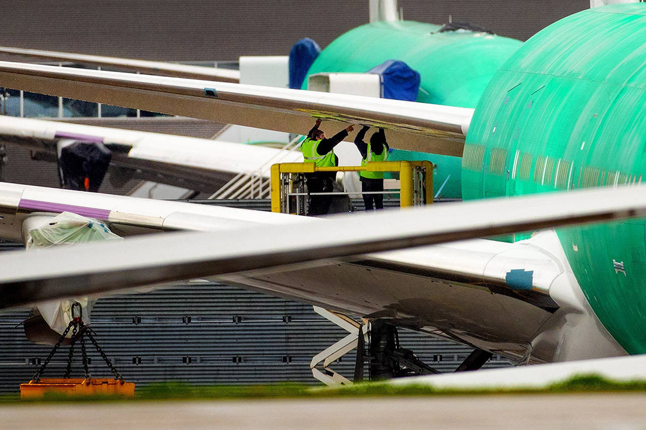 Boeing employees work on a wing section of a 777X outside the factory in Everett in April. (Mike Siegel | The Seattle Times)