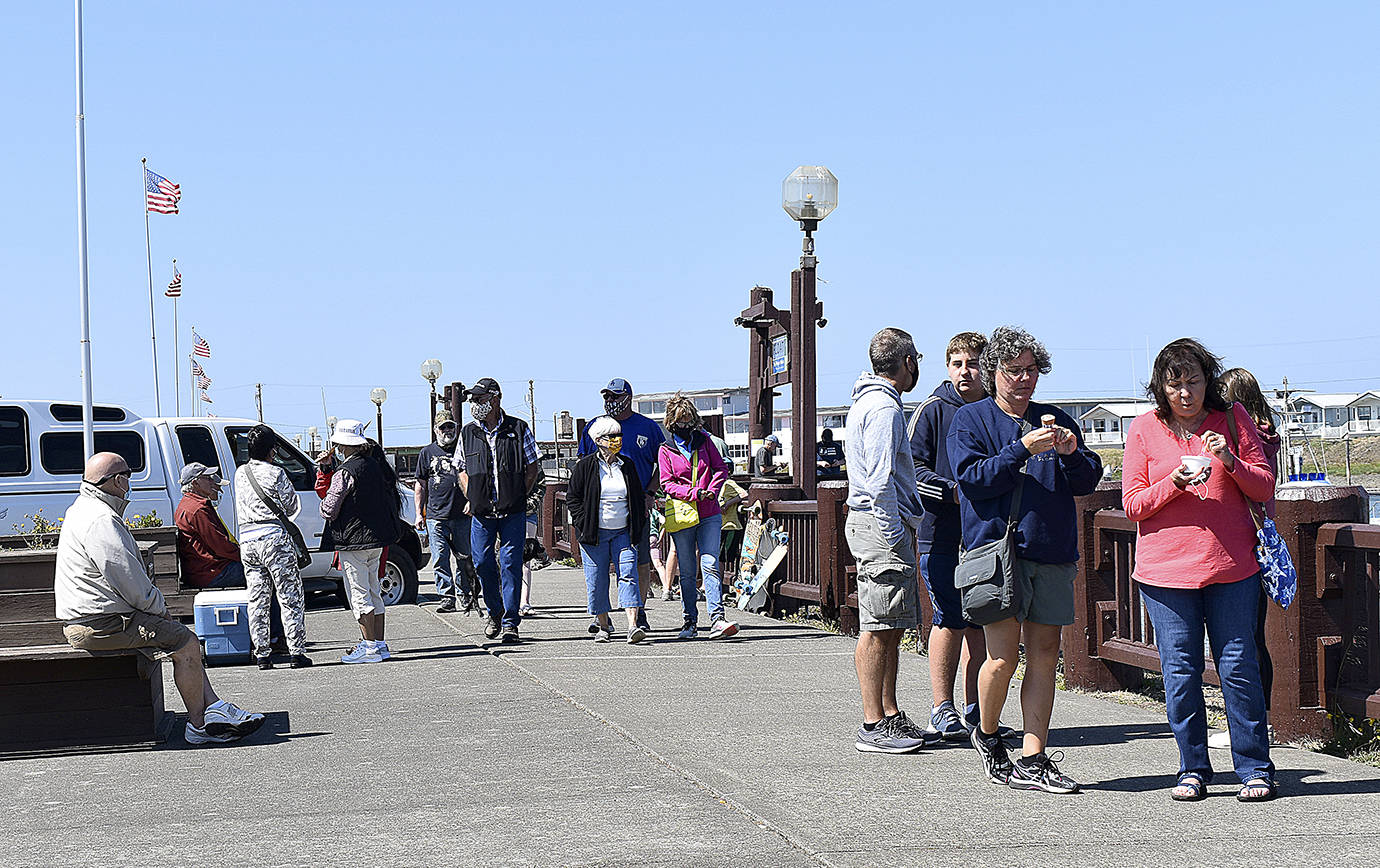DAN HAMMOCK | GRAYS HARBOR NEWS GROUP                                 People walk the boardwalk at the Westport Marina Aug. 13. Visitors wore masks when not socially distanced, dropping them only for bites of ice cream.