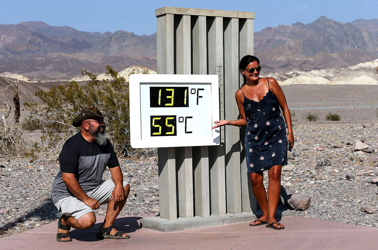 Visitors gather for a photo in front of an unofficial thermometer at Furnace Creek Visitor Center on Monday. The official temperature reached 130 degrees at Death Valley National Park on Sunday, hitting what may be the hottest temperature recorded on Earth since at least 1913, according to the National Weather Service. Park visitors have been warned, ‘Travel prepared to survive.’ (Mario Tama/Getty Images)