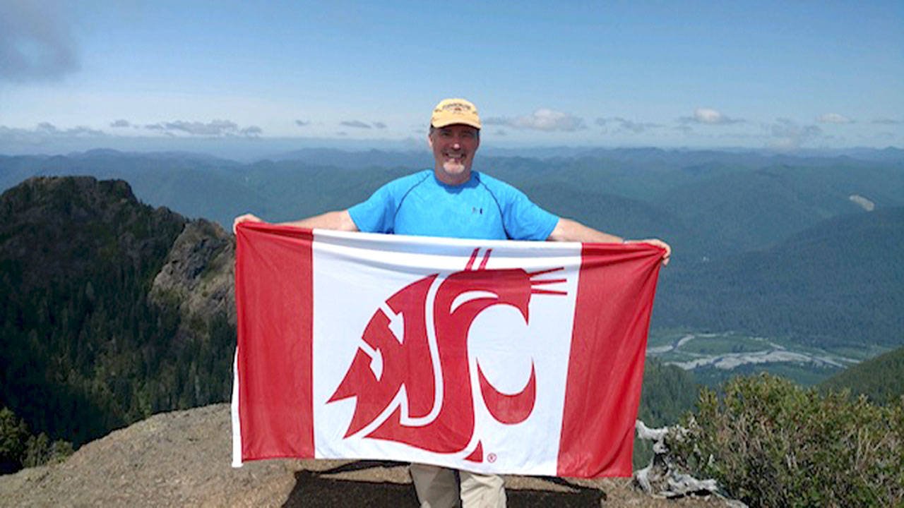Dave Ward holds the flag of his beloved alma mater during a recent “peak-bagging” hike up Colonel Bob Mountain, one of the highest points in Grays Harbor County — the highest being Gibson Peak. (Photo by Ian Cope)