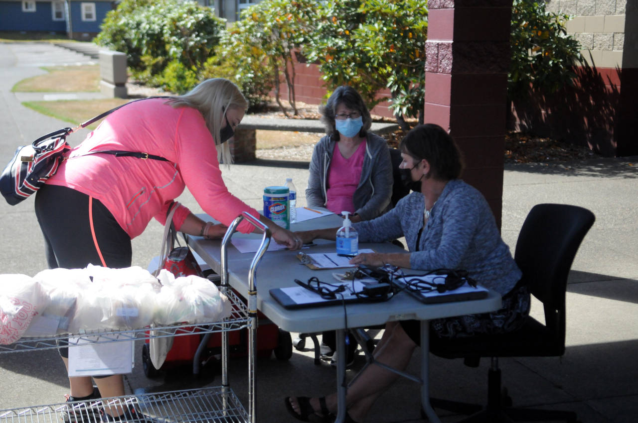 Montesano School District employee Lise Wood, right, and Joanne Rose, middle, assist a parent in a lunch pick-up during the first day of school on Wednesday in Montesano. Wood approximates that 30 lunches were handed out in the first half hour and expects that number to increase as the school year advances. Meals are available for delivery and pick-up from 11 a.m. to 1 p.m. (Ryan Sparks | The Daily World)