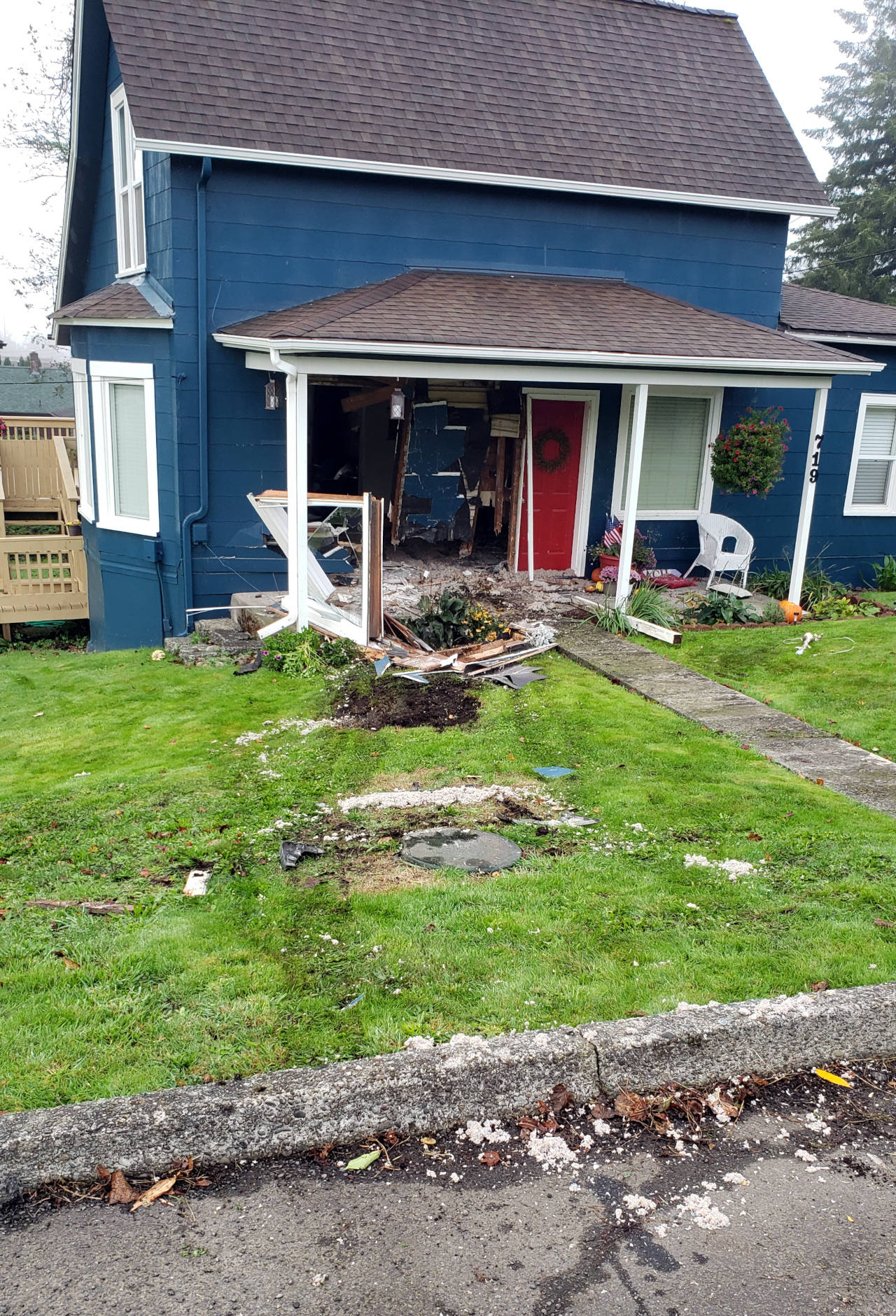 Tire tracks in the grass of a home on Pioneer Avenue show the trajectory of a passenger vehicle that veered off the road and rammed into the front of a house on Thursday morning in Montesano. (Ryan Sparks | The Daily World)