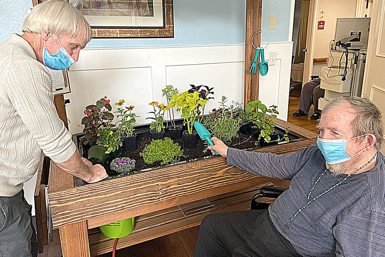 Darrald Dewald, left and Bob Kloempken work in one of the indoor gardens at Pacific Care and Rehabilitation Center.