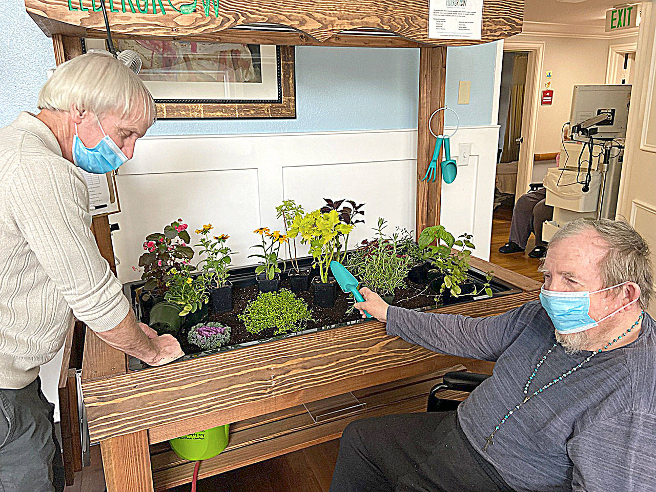 Darrald Dewald, left and Bob Kloempken work in one of the indoor gardens at Pacific Care and Rehabilitation Center.