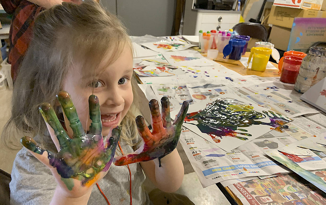 Mae Gambee, 4, did some freestyle finger-painting on Saturday in addition to decorating ornaments made from sand dollars and other materials provided by the Cosi Art Center. She was there with her mom, Sarah Gambee, and baby brother Grant. (Kat Bryant | The Daily World)