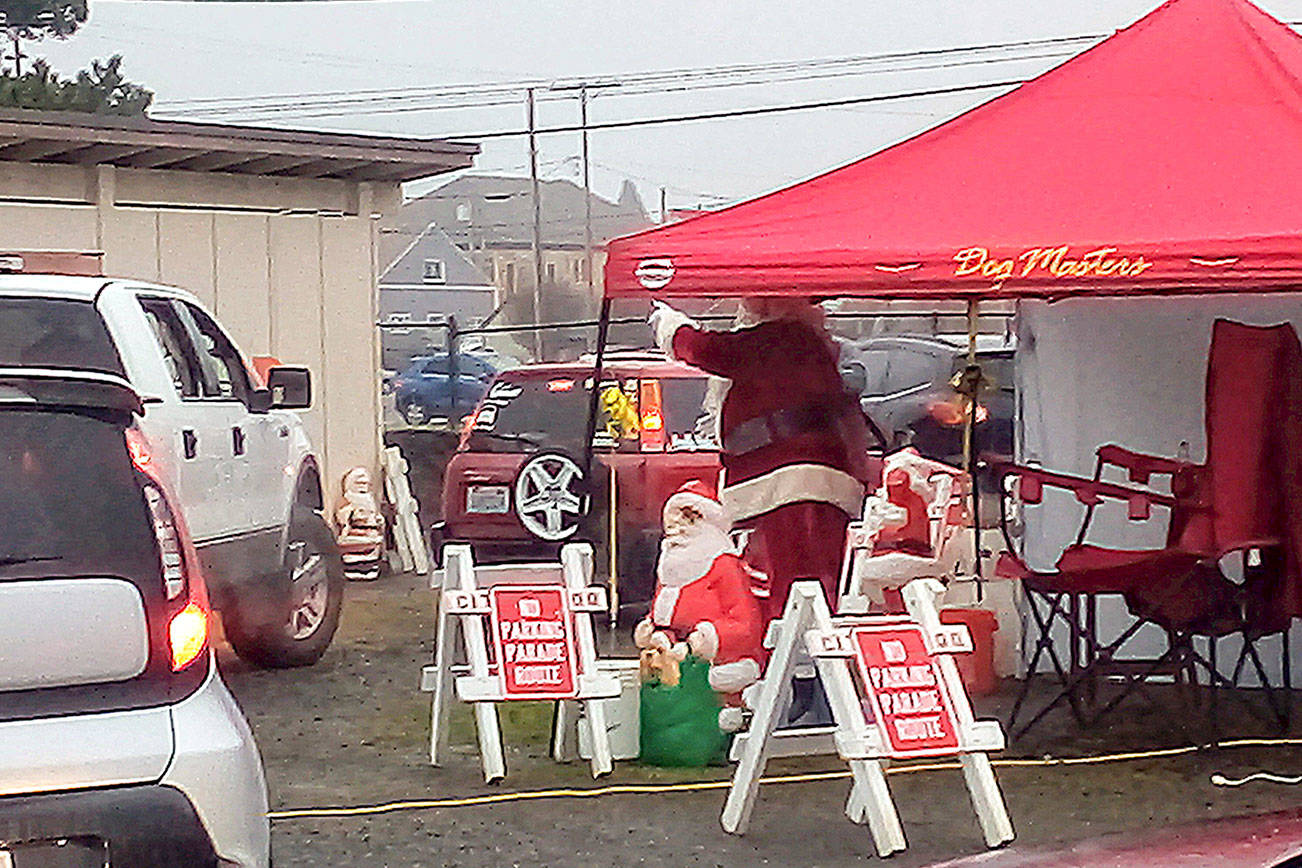 Santa Claus waves to children in slowly passing cars during the drive-through visit hosted by the Hoquiam Elks in their back parking lot last Saturday. (Photos by David Haerle)