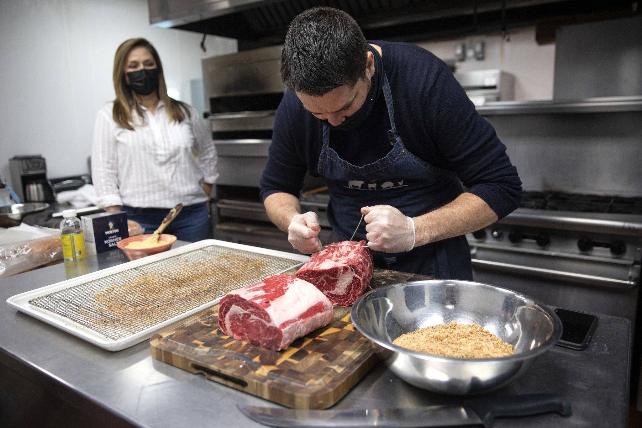 Maribel Moreno-Musillami, founder and owner of Purely Meat Co., watches chef Matt Ronan tie up a Wagyu prime rib cut Dec. 23, 2020, in Chicago. Purely Meat, which distributes meat to high-end restaurants and some grocery stores, saw its business plunge 70% at the start of the pandemic but built a direct-to-consumer website. (Erin Hooley/Chicago Tribune)