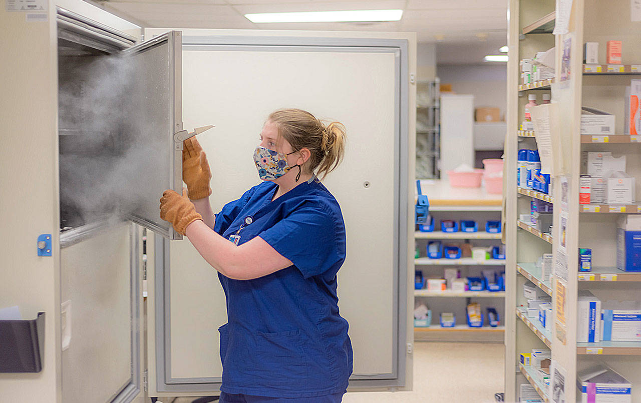 COURTESY GRAYS HARBOR COMMUNITY HOSPITAL 
Grays Harbor Community Hospital has installed its ultra-cold freezer to accommodate the necessary -75 degrees celsius needed for the Pfizer COVID-19 vaccine. Here pharmacy technician Katie Francis unboxes and stores the first Pfizer vaccine.
