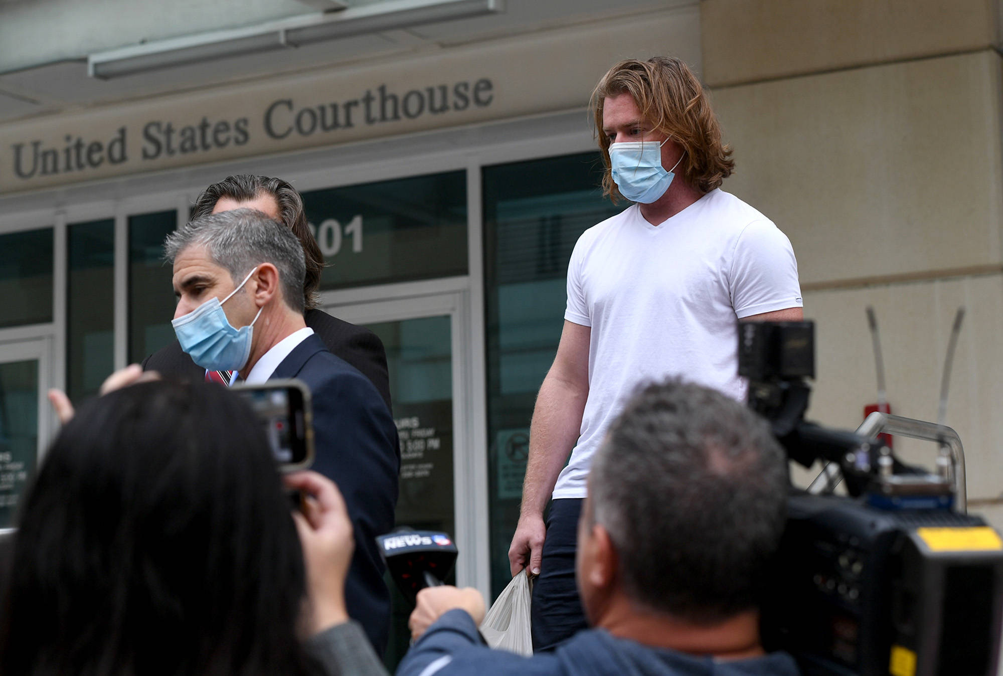 Tiffany Tompkins/Bradenton Herald 
Adam Johnson, right, emerges from the Tampa Federal Courthouse after an appearance Monday, wearing an ankle monitor.