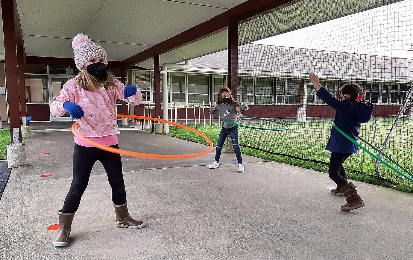 COURTESY PHOTO 
Cosmopolis second graders practicing social distancing while using hula hoops at recess. From left are Charliegh Revel and Shyla Mayr.