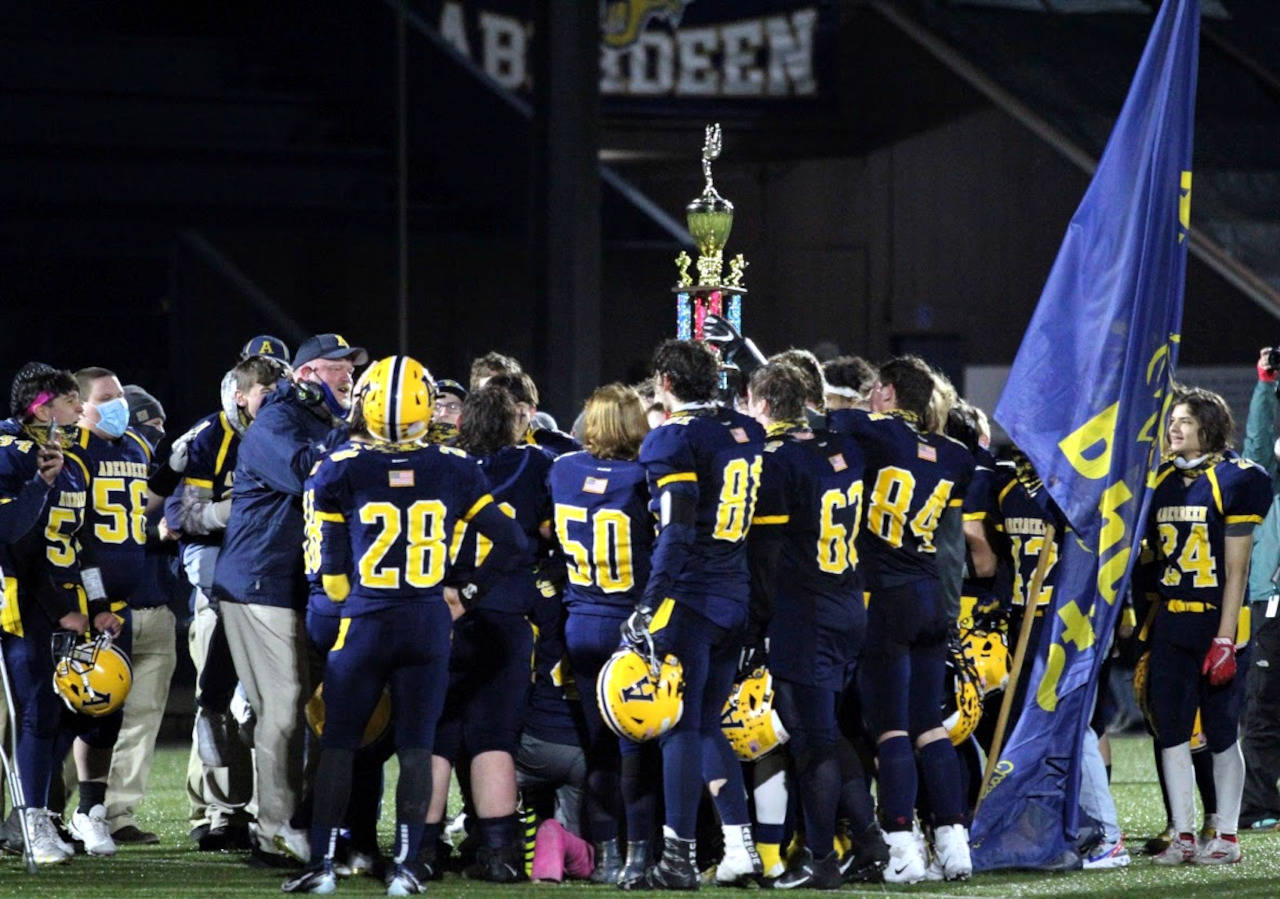 PHOTO BY BEN WINKELMAN Aberdeen head coach Todd Bridge, left, speaks with his team as the Bobcats raise the Myrtle Street Trophy after defeating Hoquiam 30-8 in the 115th Myrtle Street Rivalry game on Saturday in Aberdeen.