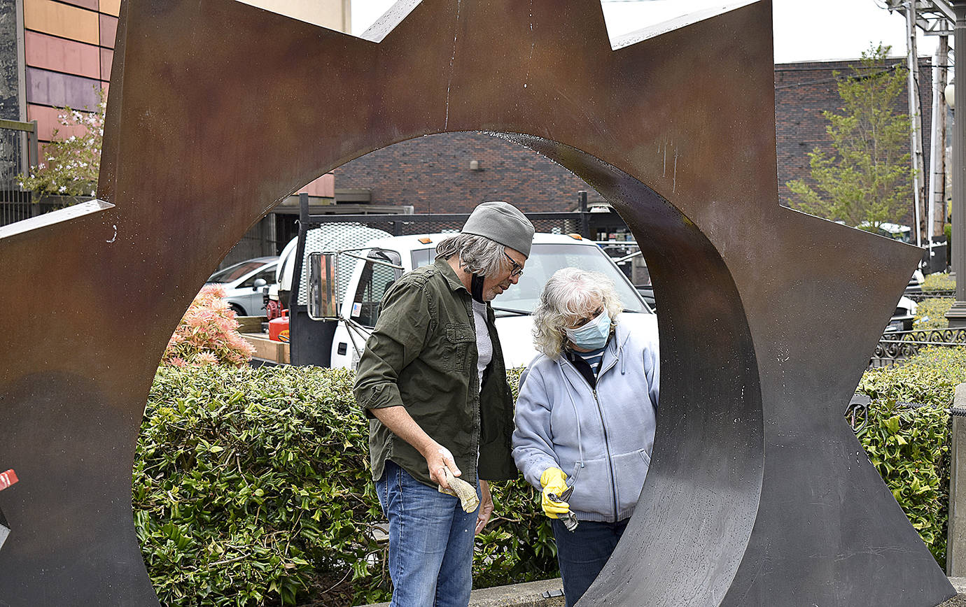 DAN HAMMOCK | THE DAILY WORLD 
Christine Peck has been cleaning the Illumination statue at the corner of East Wishkah and I Street in Aberdeen twice a year since 2014. Friday, she passed the torch to Downtown Aberdeen Association Director Wil Russoul. The installation was placed in 2005, the work of Gerard Tsutakawa, funded by the Kathryn N. Sherk bequest.