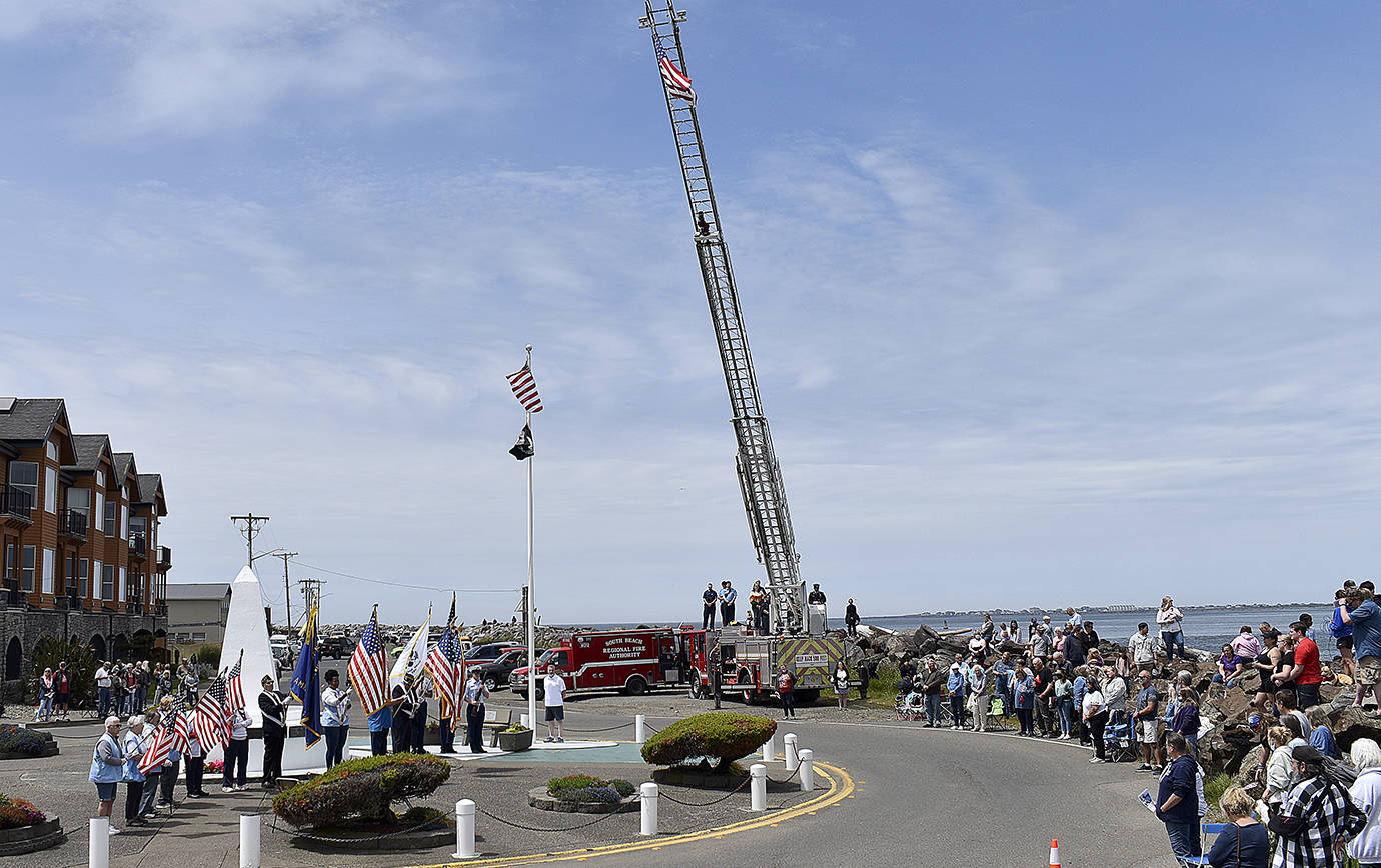 DAN HAMMOCK | THE DAILY WORLD
The presentation of the colors at Sunday’s Blessing of the Fleet in Westport. Presenting the colors were the U.S. Coast Guard and members of local veterans’ associations. At center, at the base of the flag pole, Greg Barnes prepares to ring the memorial bell as names of those who lost their lives at sea are read aloud. The ceremony began with the raising of the flag on the South Beach Regional Fire Authority ladder truck in the background.