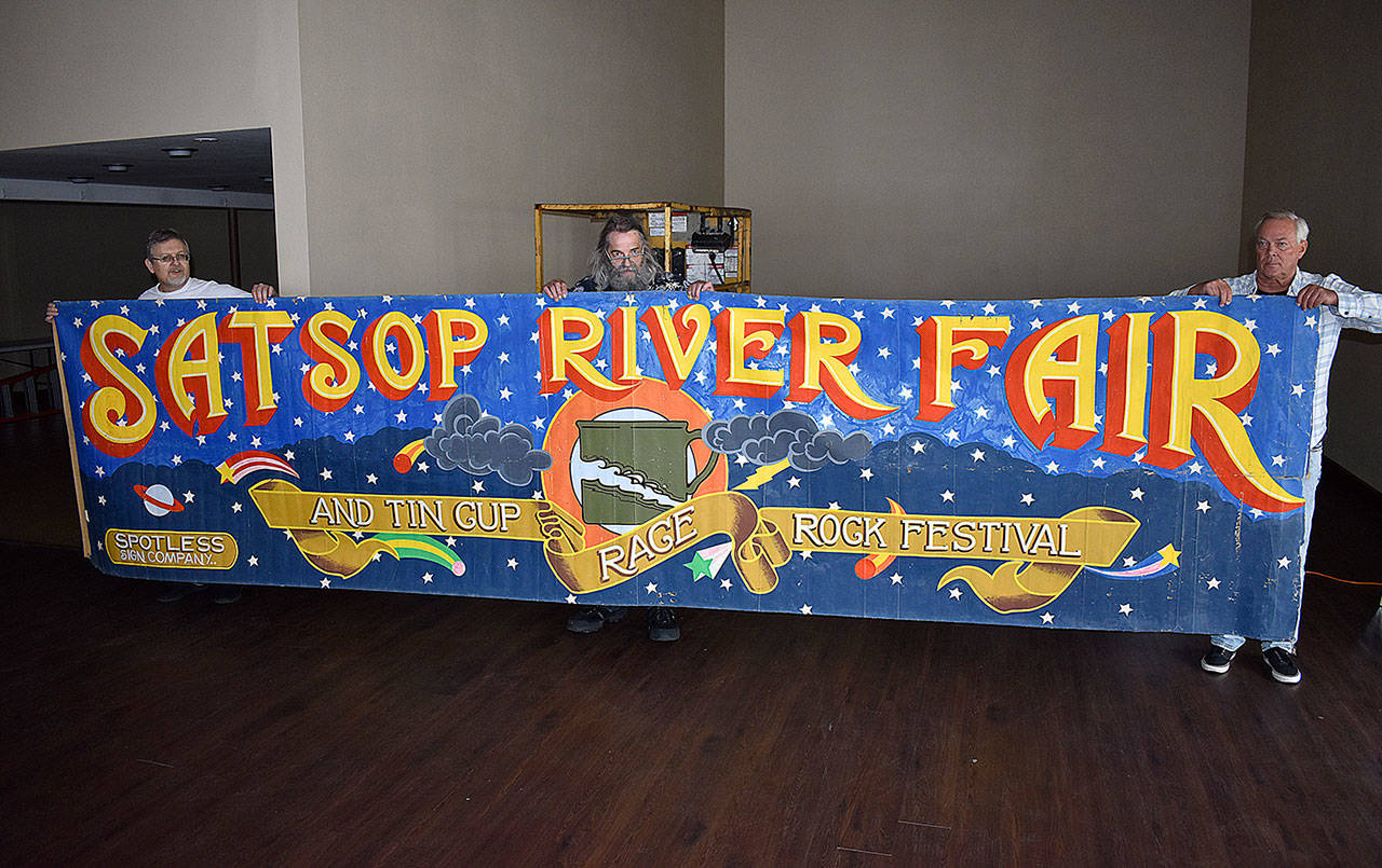 DAN HAMMOCK | THE DAILY WORLD 
Jeff Hammers brought the original 1971 Satsop River Fair and Tin Cup Race rock festival banner to the D&R Events Center in Aberdeen on Wednesday. At left is Randy Beerbower from the Chehalis Valley Historical Society, and at right is John Kirkwood, who attended the festival.