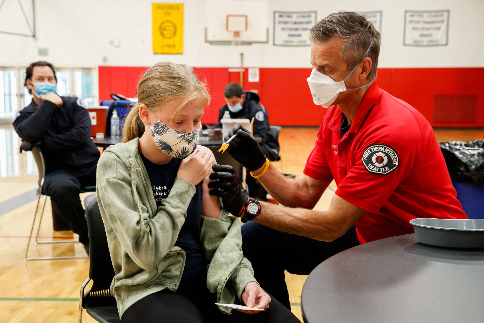 Seattle Firefighter and EMT Garth Stroyan administers a COVID-19 vaccination for Asya Strounine, 13, an eighth grader at Jane Addams Middle School, at Nathan Hale High School in Seattle on June 10, 2021. Strounine says she was a little nervous about the vaccination, but is looking forward to having more protection against COVID-19. Erika Schultz | The Seattle Times