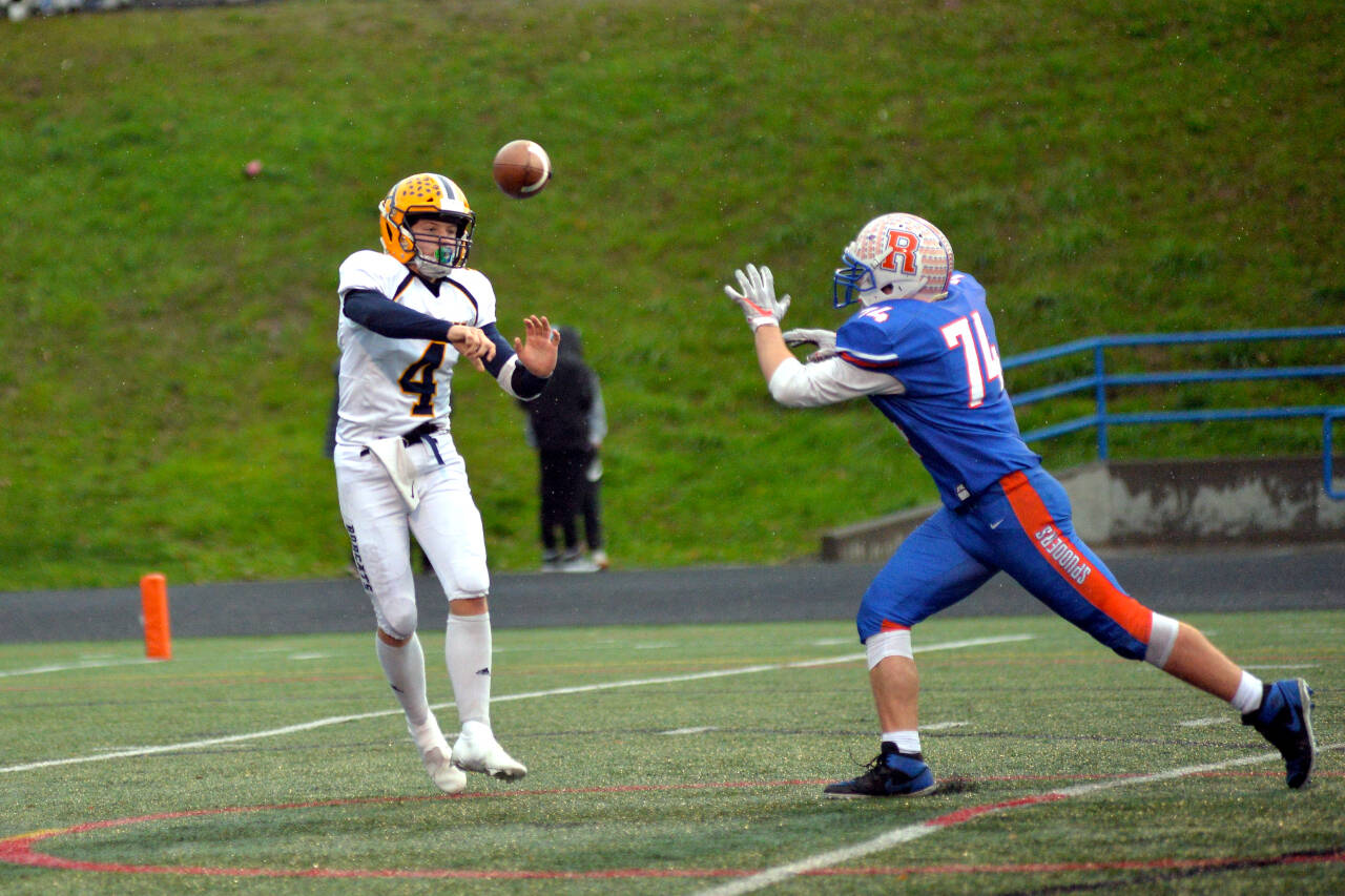 RYAN SPARKS | THE DAILY WORLD Aberdeen quarterback Kale Goings (4) throws a pass while being pursued by Ridgefield defensive lineman Daniel McDonnell during the Bobcats 28-0 loss to the Spudders in a 2A district playoff game on Saturday in Ridgefield.